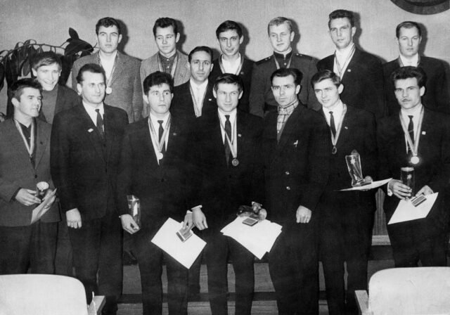 „Minijos“ futbolininkai po apdovanojimo 1964 m. gruodžio 26 d.: pirmoje eilėje (iš kairės) Kazimieras Mačiulskis, laikraščio „Sportas“ redaktoriaus pavaduotojas Algirdas Kazilionis, Stasys Bajelis, Algirdas Andriuškevičius, Kretingos rajono vykdomojo komiteto pirmininko pavaduotojas Aloyzas Opulskis, Romualdas Skurvydas, Ramutis Trumpenskas, antroje eilėje – Eduardas Milius, Vytautas Vilkas, Vladas Eitavičius, Vaclovas Brazdeikis, Romas Šalnis, Auseklis Birgelis, Stasys Galdikas, Edvardas Valatka. 1964 m. nuotr. iš Trumpenskų šeimos archyvo