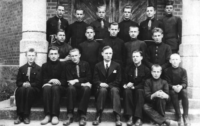 Kretingos pranciškonų gimnazijos V klasė, įsiamžinusi prie bažnyčios 1933 m. birželio mėn. Centre – mokytojas Andrius Kirtiklis, pirmoje eilėje 2-as iš kairės – Viktoras Gidžiūnas.Nuotr. iš autoriaus skaitmeninio archyvo